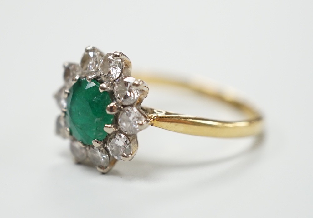 An 18ct, emerald and diamond set circular cluster ring, size K, gross weight 3 grams.